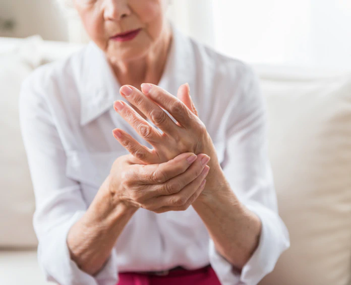 An elderly woman massaging her hand, representing the importance of bone and joint health supplements for mobility and comfort.