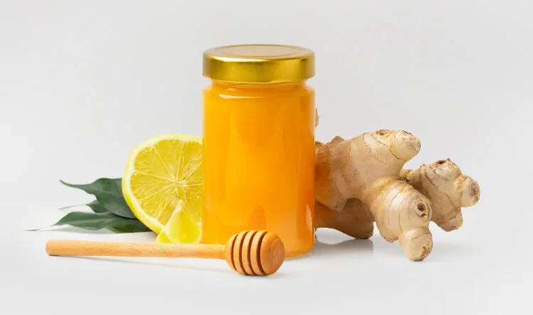 A jar of honey with lemon, ginger, and a honey dipper, representing natural remedies and supplements for immune system support.