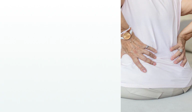 A woman sitting on a couch holding her lower back, representing the need for supplements for kidney health.