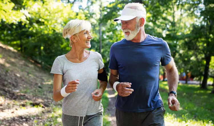 A senior couple jogging outdoors, smiling and enjoying an active lifestyle supported by supplements for optimal health.