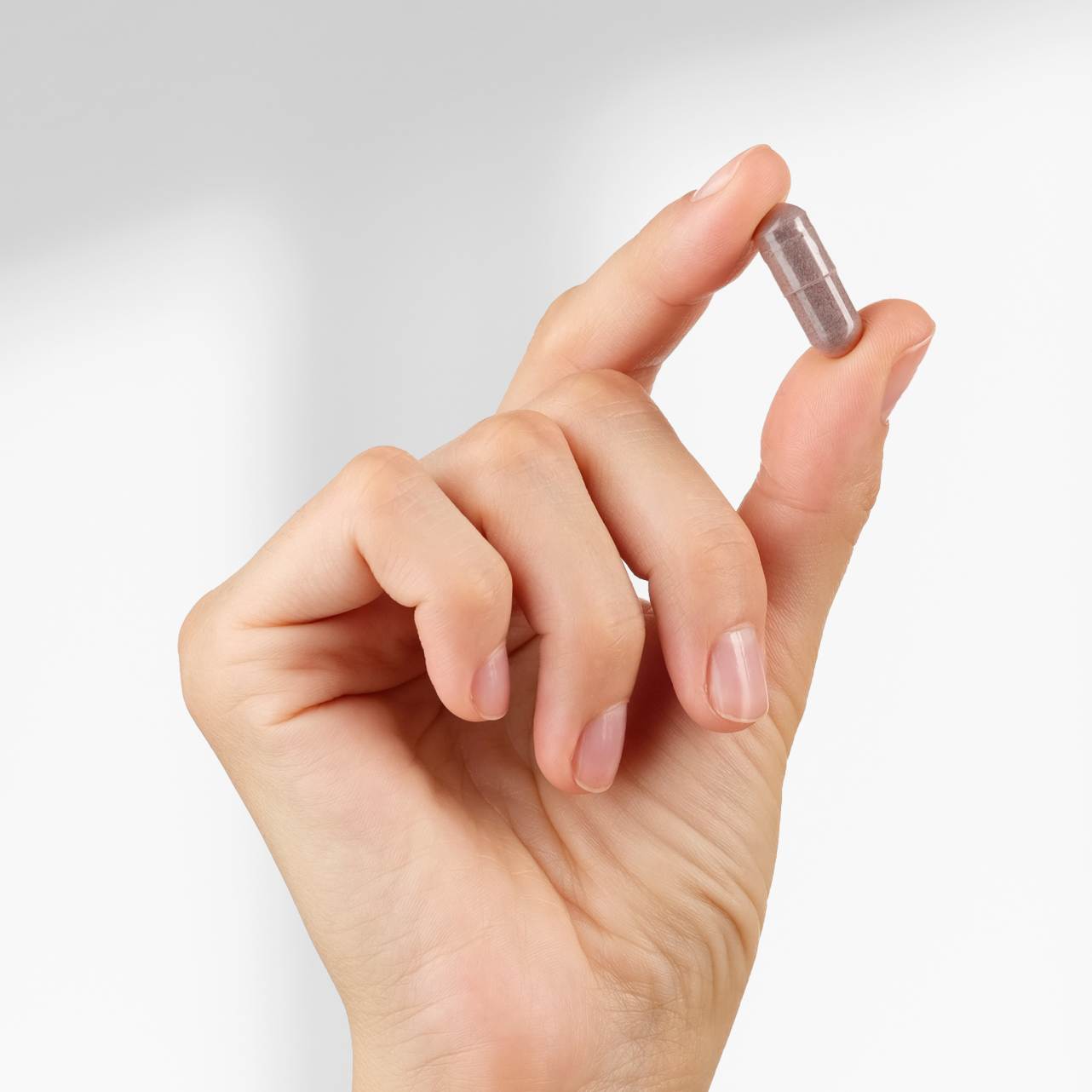 Hand holding a capsule of Complete Vision Formula dietary supplememt