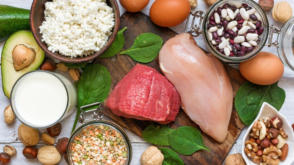 A close-up image displaying a variety of Vitamin B6-rich foods, including raw beef, chicken breast, a jar of mixed beans, avocado.