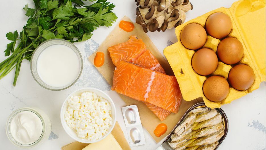 A top-down image displaying a variety of Vitamin D-rich foods, such as salmon, eggs, and mushrooms.